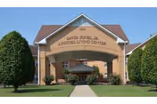 Front exterior of David Jones, Jr. Assisted Living Center with a covered entrance archway, walkway, and landscaped trees.