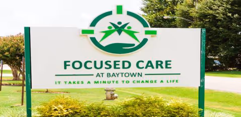 Outdoor sign for Focused Care at Baytown with green logo in front