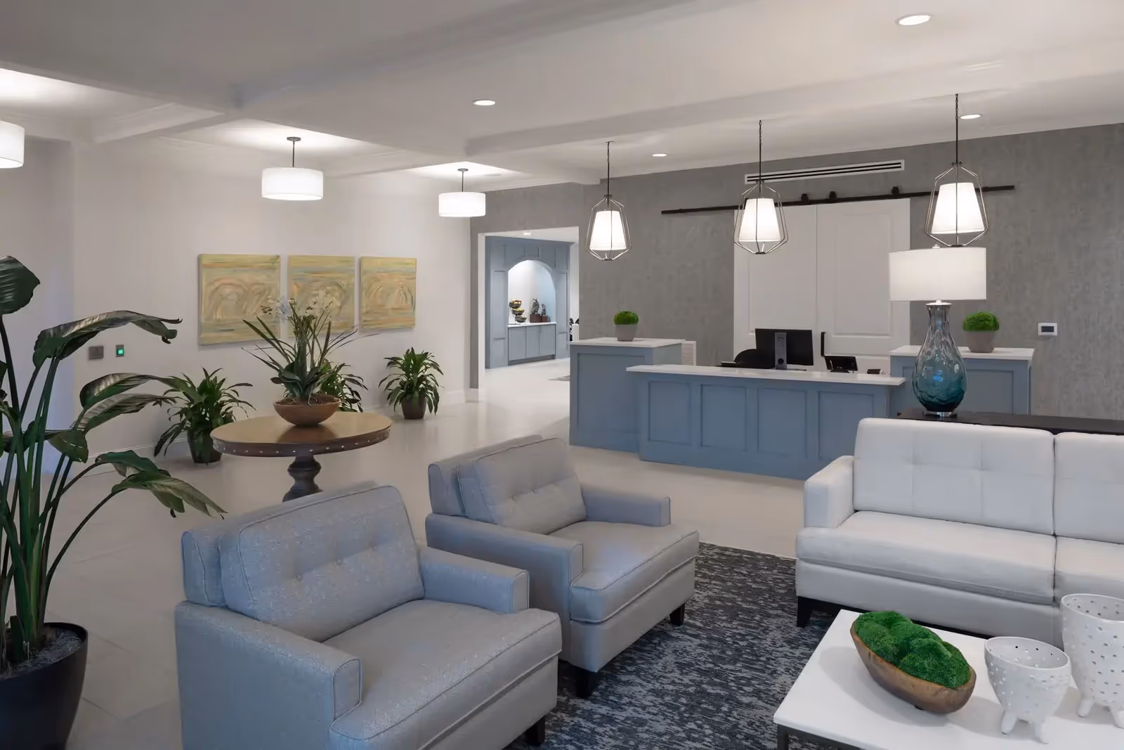 Bright modern lobby with seating, plants, and a reception desk.