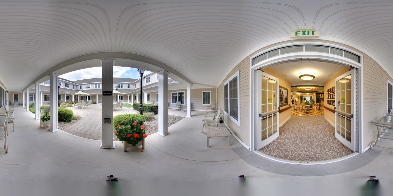 Covered porch with columns overlooking a landscaped central courtyard and open double doors leading into the senior living facility.