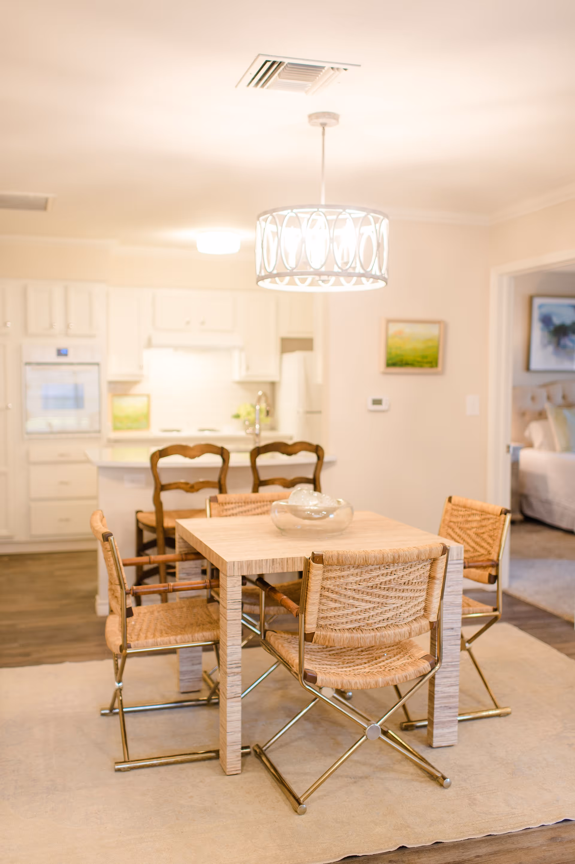Bright dining area with a wooden table and woven chairs in an open-plan kitchen and living space.