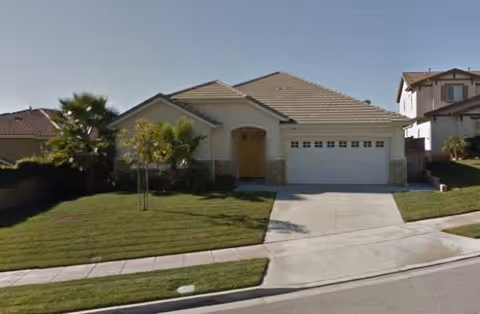 Front exterior of a single-story home with a two-car garage and manicured lawn.