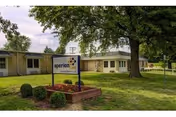 Single-story Arcadia Care Jacksonville facility with a sign, green lawn, and leafy trees.