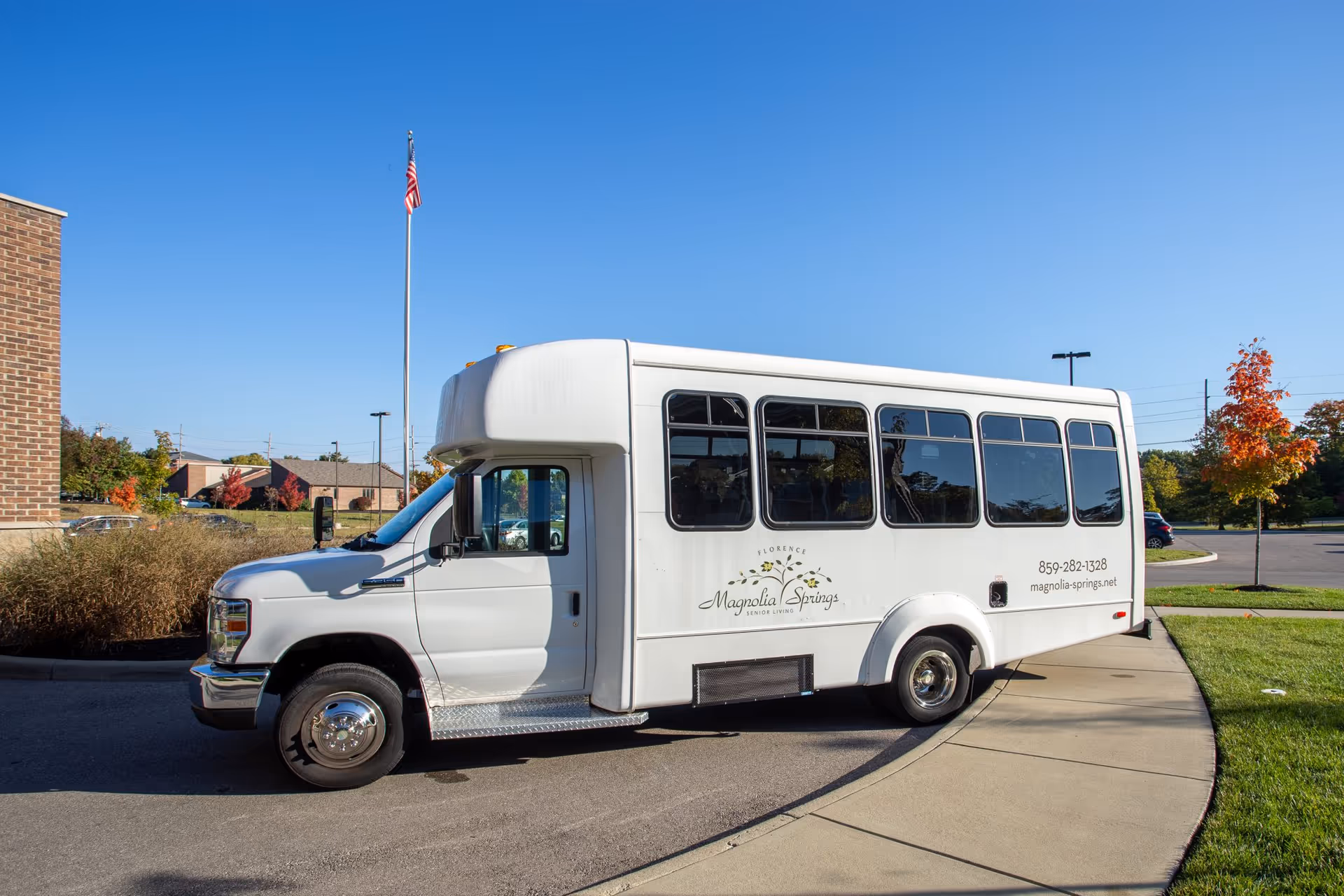 A white Magnolia Springs shuttle bus parked outside the facility on a sunny day.