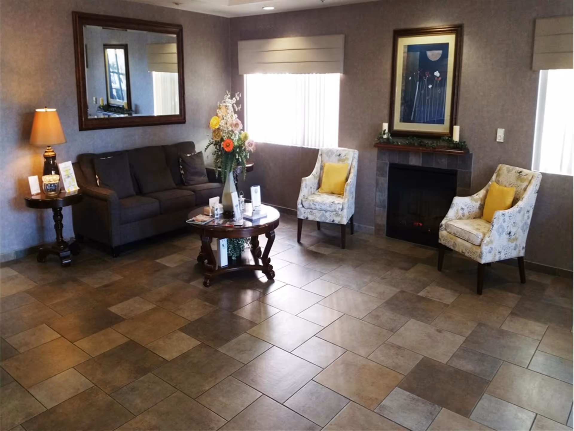 A cozy common area with a sofa, two armchairs, a coffee table, and a fireplace.