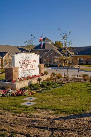 Crestview Court entrance sign with landscaped front yard and building entrance.