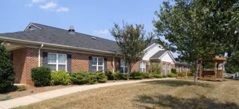 Front exterior of a single-story brick senior living facility with shrubs.