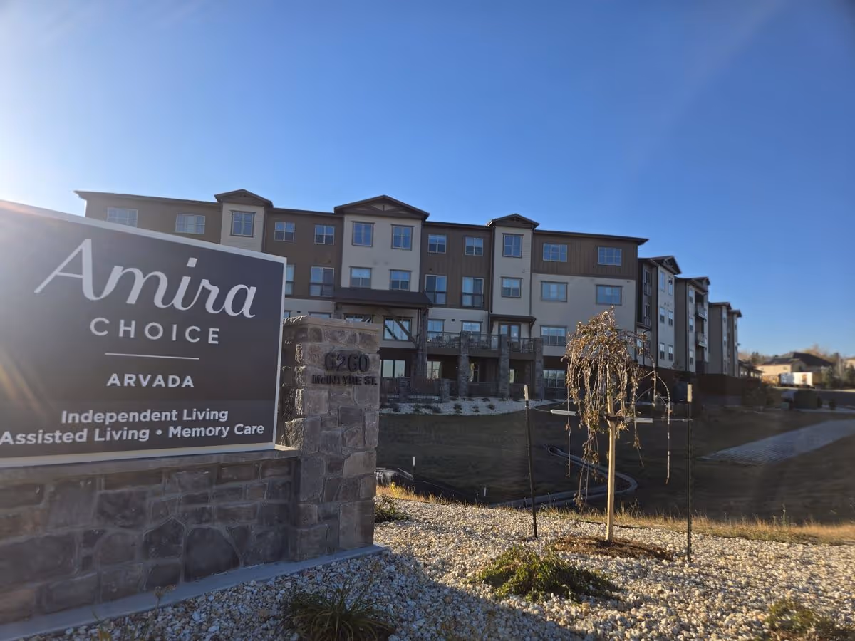 Exterior front of the Amira Choice Arvada senior living building with a large sign in the foreground.