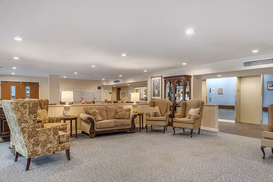 Spacious lounge area with sofas, upholstered armchairs, side tables and lamps on a patterned carpet.