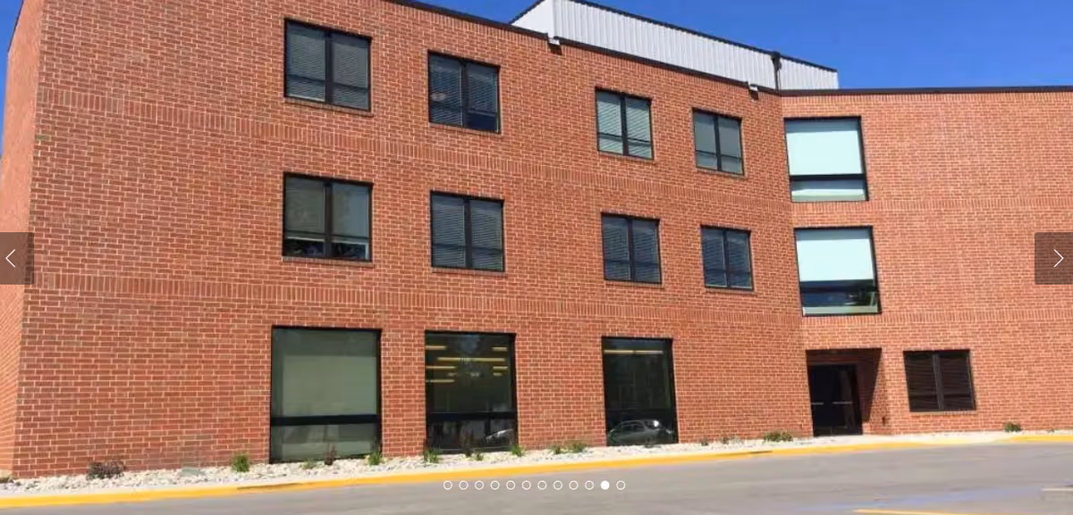 Exterior view of a three-story brick building with multiple windows and a clear blue sky above.