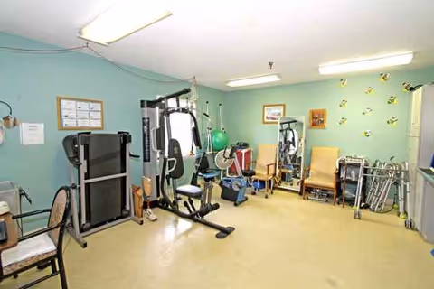 An indoor rehab gym in a senior living facility with exercise equipment.