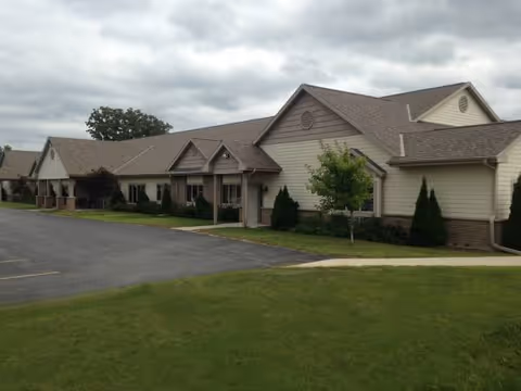Arbor View senior living facility exterior with beige siding, driveway, and manicured landscaping.