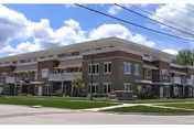 Mayflower Community brick senior living building with balconies and a manicured lawn.