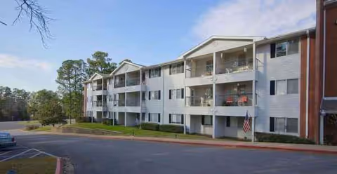 Exterior view of Colonial Village senior living building with balconies and a parking lot.