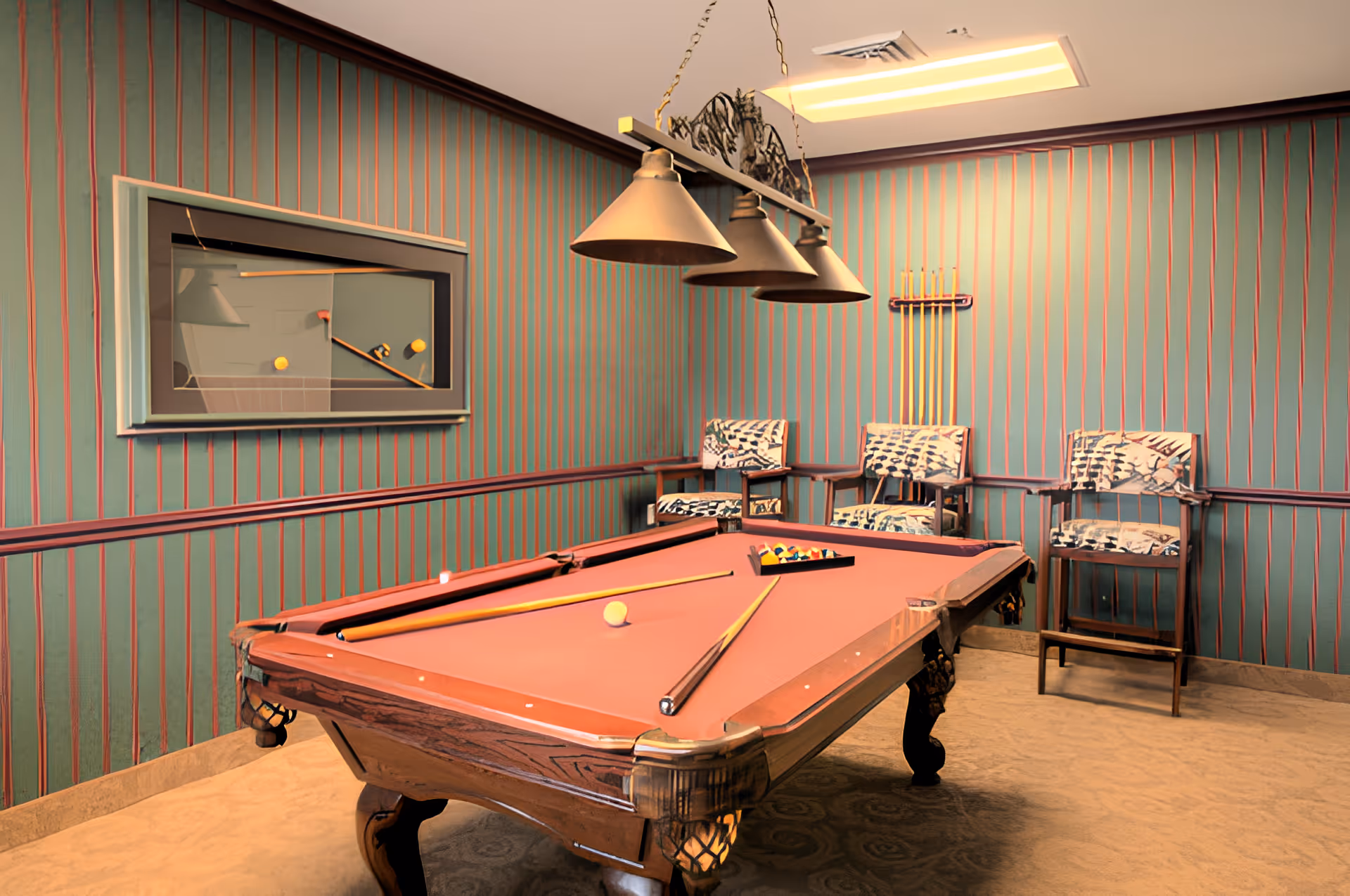 A billiards room with a pool table featuring a red felt surface, two pool cues resting on the table, and a rack of billiard balls. The room has teal walls with vertical red stripes, three patterned chairs against the wall, a wall-mounted cue rack holding four cues, and a hanging light fixture with three lamps above the pool table.