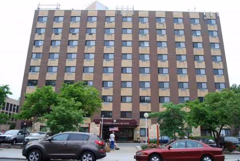 Front view of New Vanderbilt Skilled Nursing Facility, a brick building with cars parked out front.