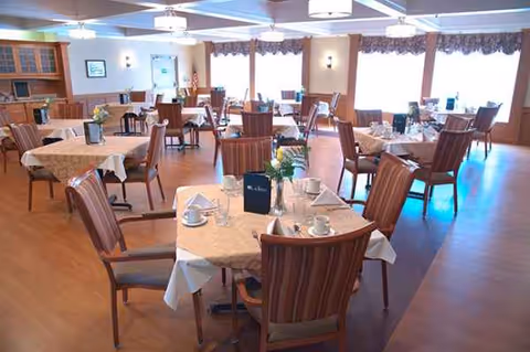 Spacious dining room with tables set for meals and wooden chairs.