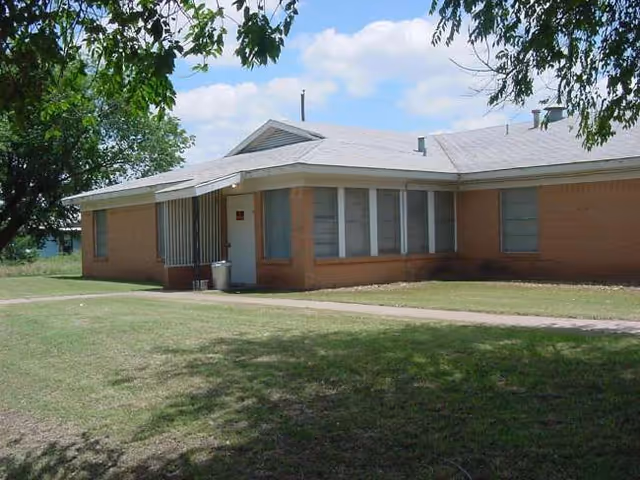 Exterior of a single-story brick building with large windows and surrounding lawn.
