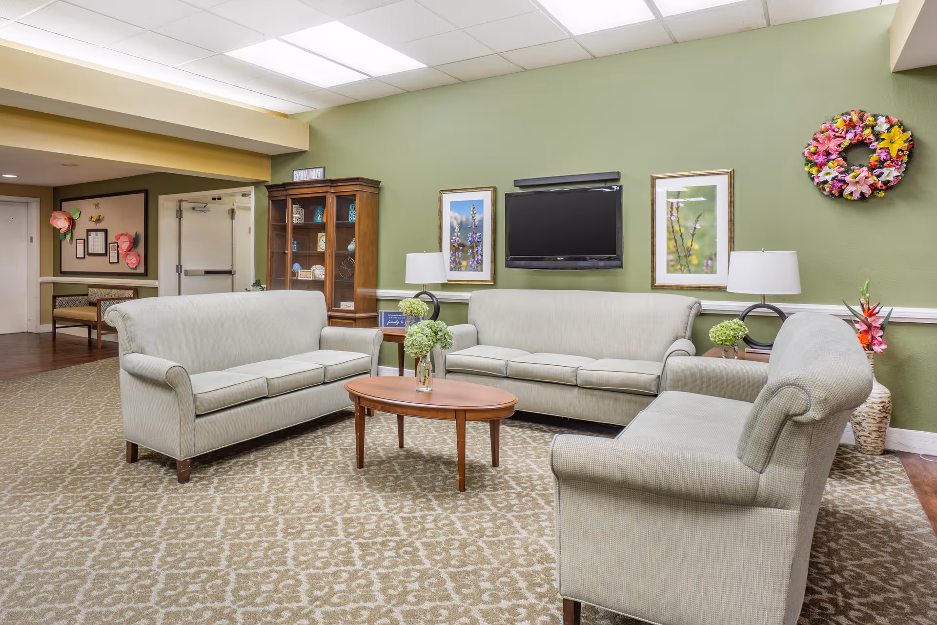 Common lounge area with sofas, a coffee table, wall-mounted TV, and framed artwork.