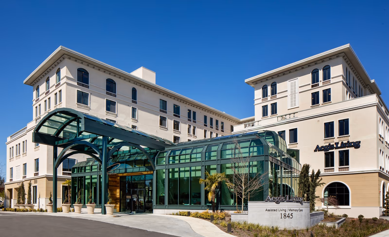 Exterior view of Aegis Living Bellevue Overlake, a multi-story assisted living and memory care facility with a modern glass entrance canopy and clear blue sky.