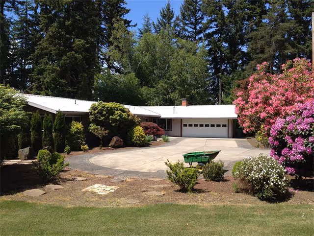 Exterior view of a senior living facility surrounded by colorful landscaping and trees.