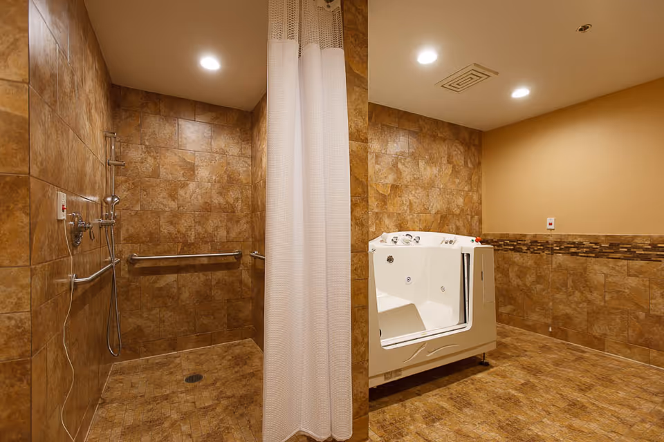 Tiled accessible bathroom featuring a walk-in shower with grab bars and a white walk-in bathtub separated by a shower curtain.