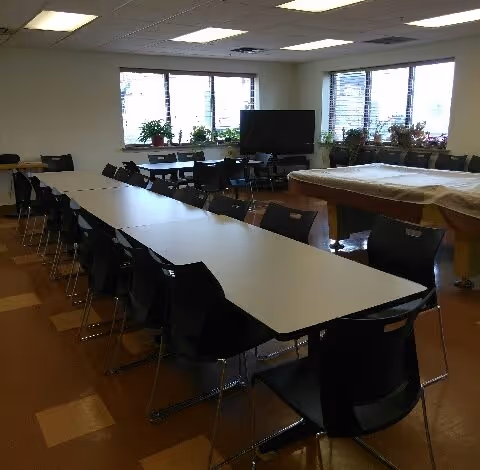 A long dining room with rows of chairs, tables, and large windows.