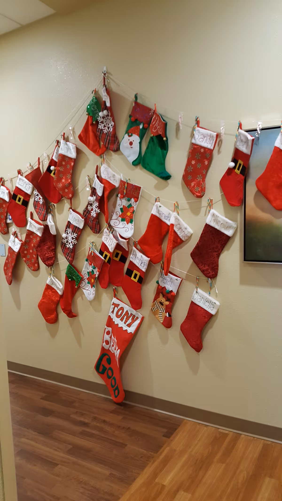 A hallway wall decorated with many red and green Christmas stockings hung in rows.