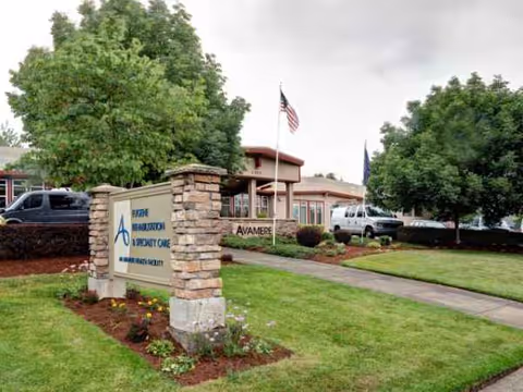 Exterior view of Avamere Rehabilitation of Eugene with entrance sign and flagpoles.