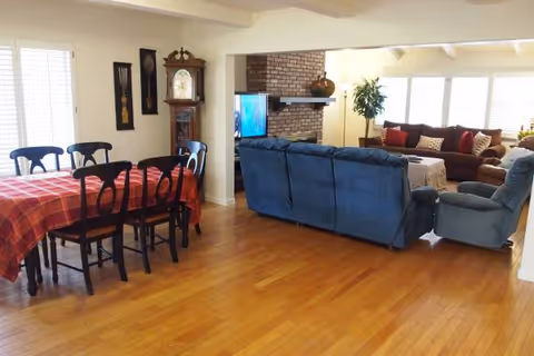 Open-concept living and dining area with blue sectional seating and a brick fireplace.