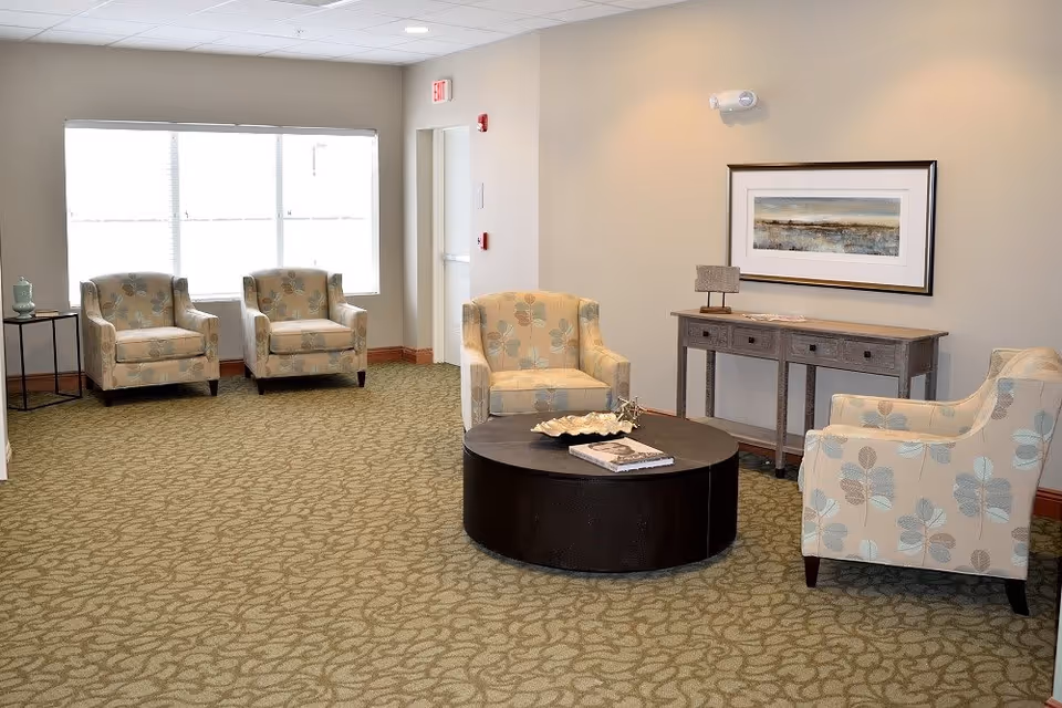 A bright seating area with patterned armchairs arranged around a round coffee table in a communal room.