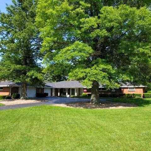 Front exterior of Sunset Haven with green lawn, trees, and a covered entrance.