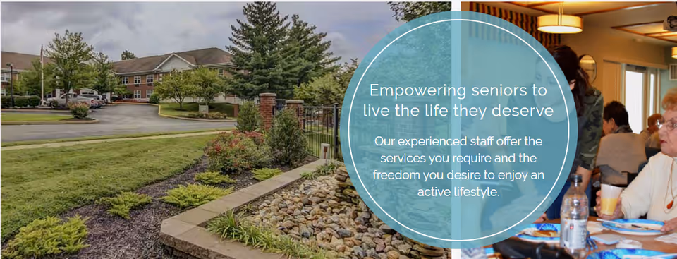 View of the exterior grounds of a senior living facility with a landscaped garden featuring rocks and plants in the foreground, a paved driveway, and a multi-story brick building in the background. On the right side, seniors are seated indoors at a dining table, eating and drinking. Overlaid text in a blue circle reads: 'Empowering seniors to live the life they deserve. Our experienced staff offer the services you require and the freedom you desire to enjoy an active lifestyle.'
