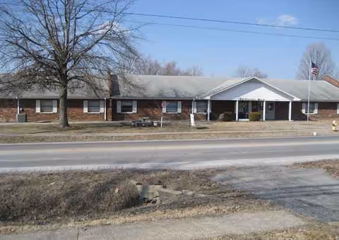 Single-story brick senior living facility with front entrance and flagpole.