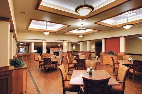 A spacious dining room with multiple tables, chairs, and a fireplace.