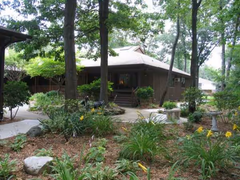 Exterior view of Lakeshore Woods facility with landscaped garden and trees around the entrance
