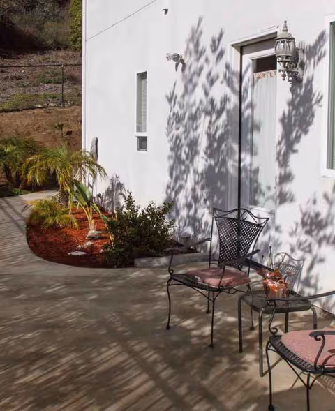 Patio seating with metal chairs and cushions beside a white building.