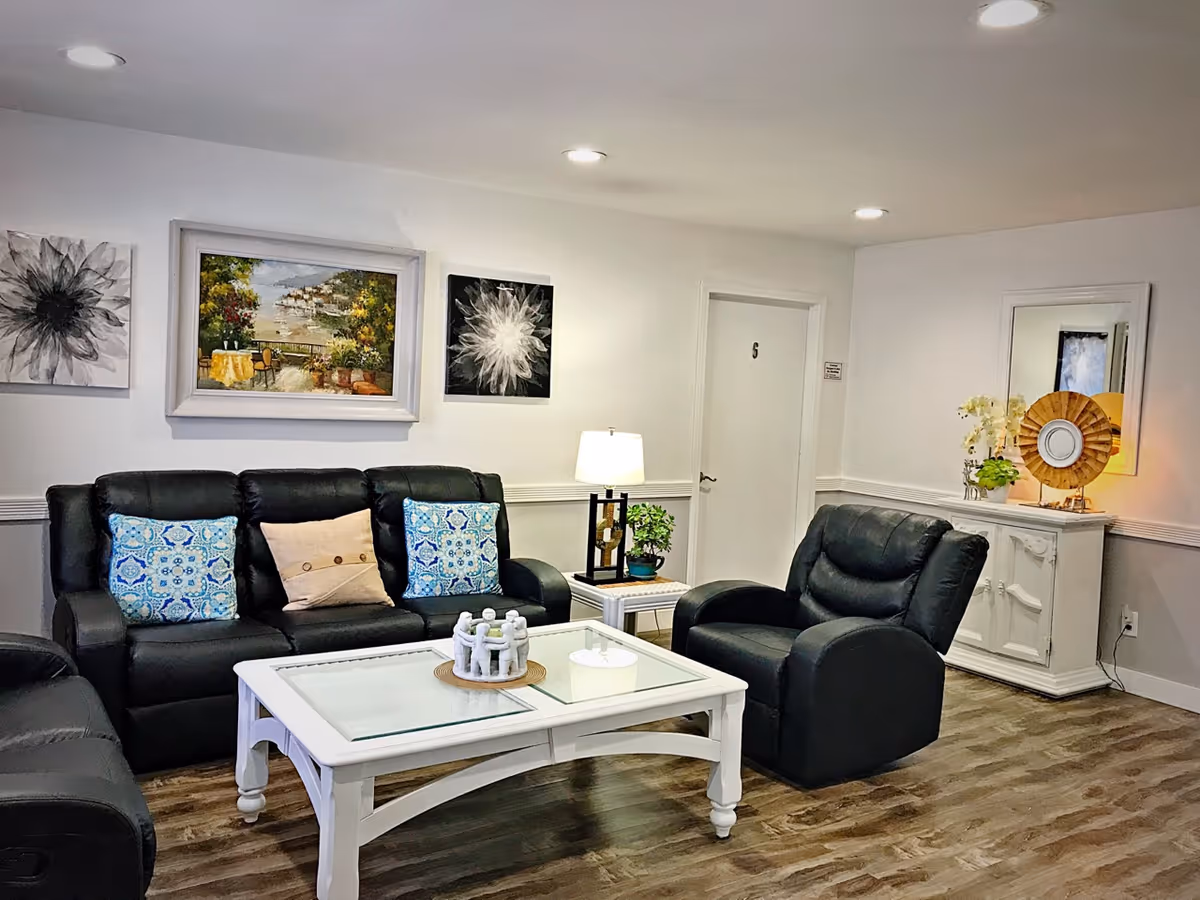 Bright, airy living room with black leather seating and decorative wall art.