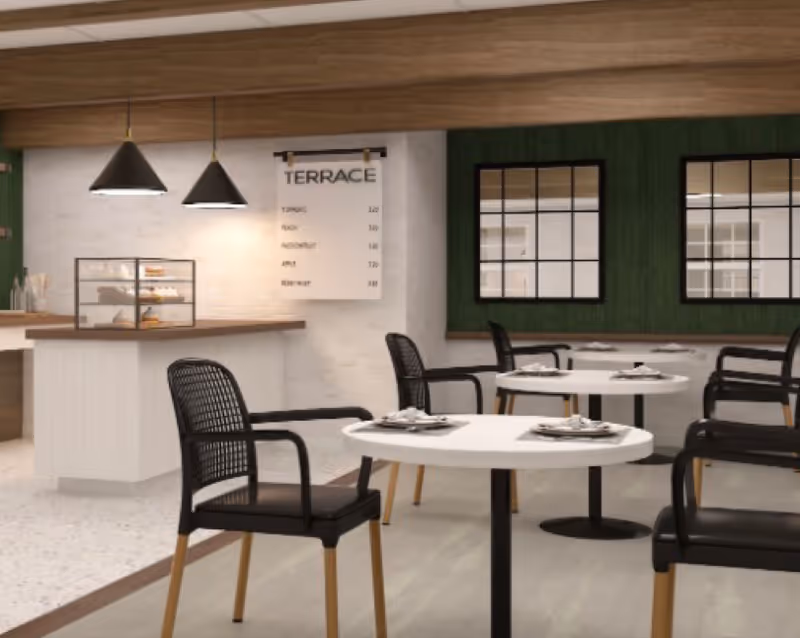 A modern dining area with round white tables and black chairs with wooden legs. There are two black pendant lights hanging over a counter with a glass display case containing pastries. A menu board labeled 'TERRACE' is mounted on the wall, listing various items and prices. The walls have a combination of white and dark green panels with two large windows featuring black frames.