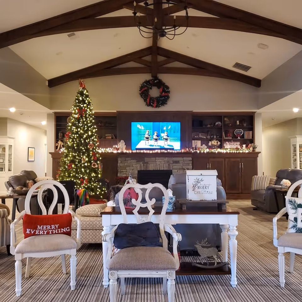Festive senior living room with Christmas tree, holiday decor, and a lit fireplace.