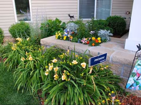 Front exterior of Pine Manor Estates with a stone planter and blooming flowers.