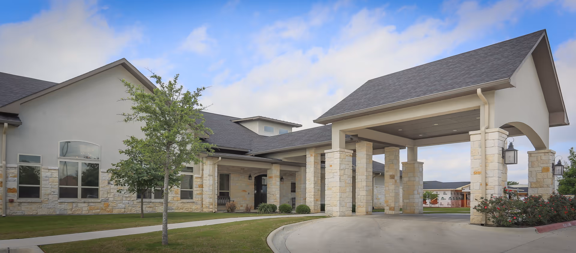 Front exterior view of Arbor House Assisted Living and Memory Care with a covered entrance supported by stone columns.
