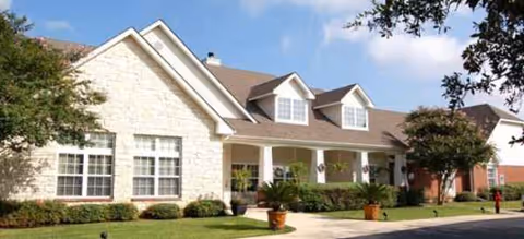 Exterior view of a single-story assisted living facility with front walkway and landscaping