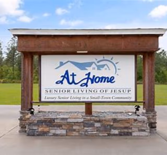 Exterior sign for At Home Senior Living of Jesup mounted on a stone base.