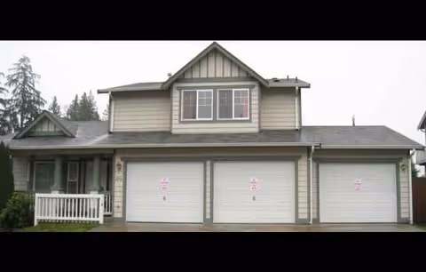 Front view of a house-style facility with three garage doors and a small porch.