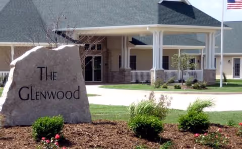 Exterior view of The Glenwood Assisted Living entrance with rock sign and landscaping.