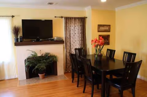 A dining area with a dark wood table, black chairs, and yellow walls.