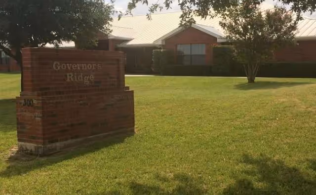 Front exterior of Governor's Ridge Retirement and Assisted Living with brick sign and lawn.