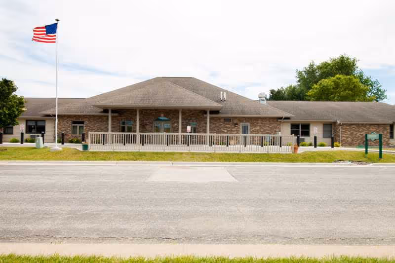 Exterior view of The Heights Assisted Living building with a front porch and flag.