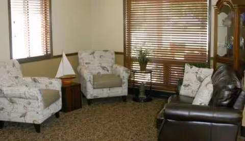 Cozy living room with upholstered chairs, a leather sofa, and window blinds.
